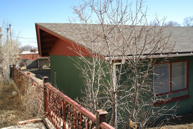 view of property exterior with a shingled roof and fence