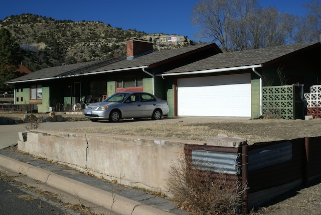 view of home's exterior with roof with shingles, driveway, a chimney, and an attached garage