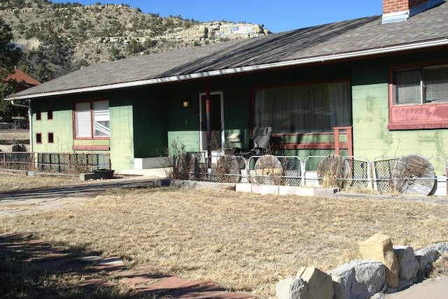 back of property with a chimney, concrete block siding, and fence