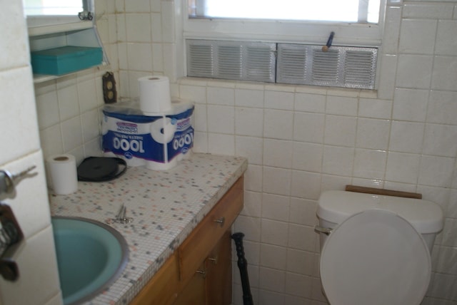 half bathroom with toilet, tile walls, and vanity