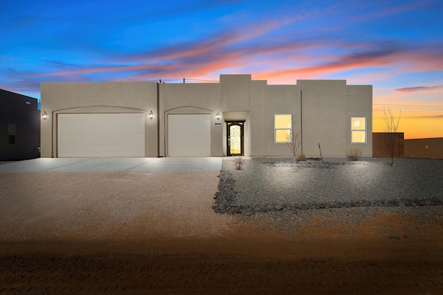 adobe home with a garage, driveway, and stucco siding