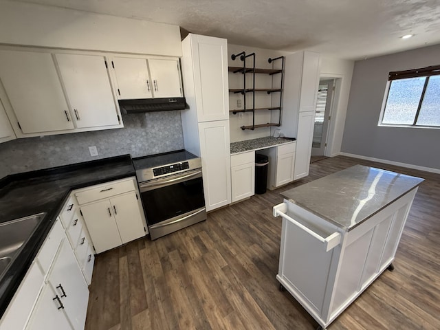 kitchen featuring electric stove, built in desk, dark countertops, and white cabinets