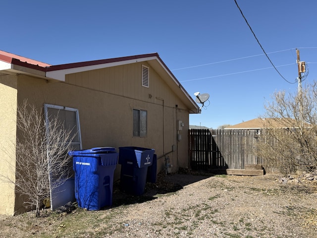 view of side of property with fence and stucco siding