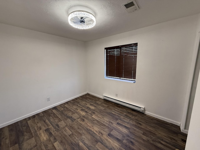 spare room featuring a textured ceiling, dark wood-type flooring, visible vents, baseboards, and baseboard heating