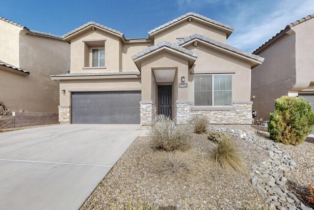 mediterranean / spanish home with stone siding, stucco siding, concrete driveway, and a garage