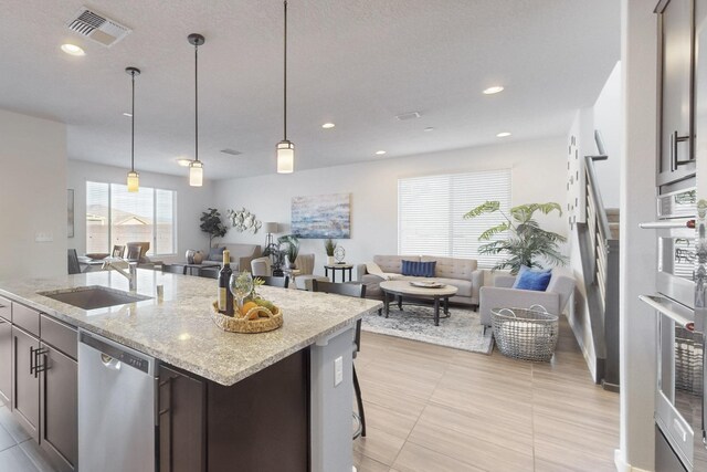 kitchen with visible vents, a sink, appliances with stainless steel finishes, pendant lighting, and open floor plan