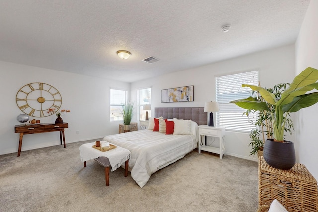 bedroom with baseboards, light colored carpet, visible vents, and a textured ceiling