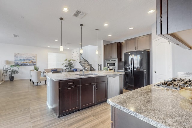 kitchen with visible vents, black refrigerator with ice dispenser, stainless steel dishwasher, a sink, and an island with sink