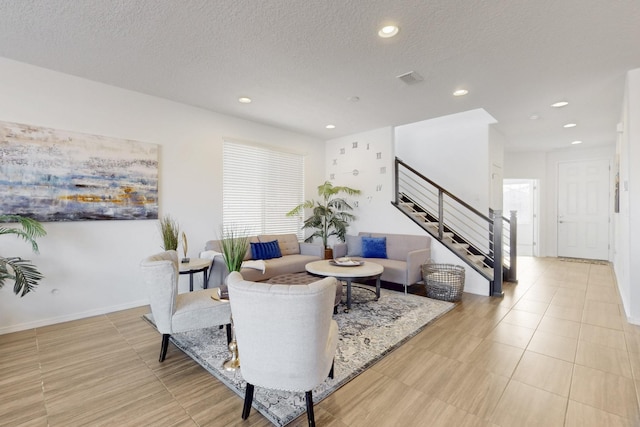 living area with recessed lighting, visible vents, stairway, and a textured ceiling