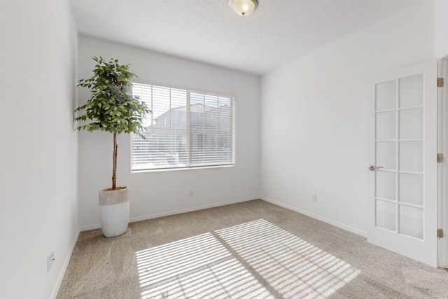 carpeted spare room featuring baseboards