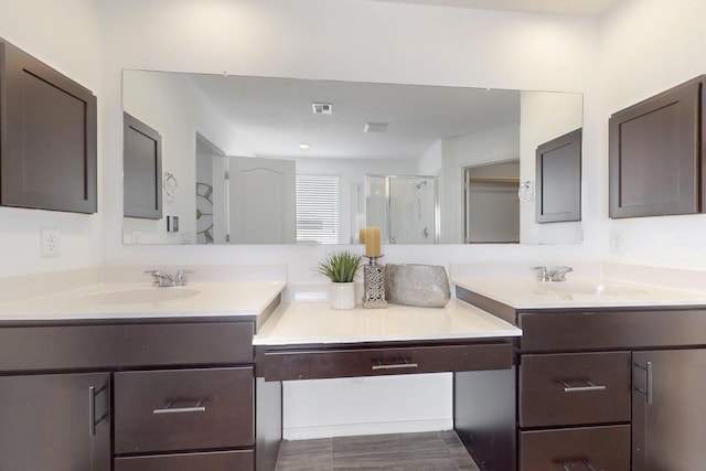 bathroom with two vanities, a stall shower, visible vents, and a sink