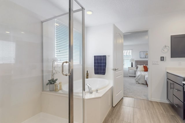 ensuite bathroom with a stall shower, connected bathroom, vanity, a textured ceiling, and a bath