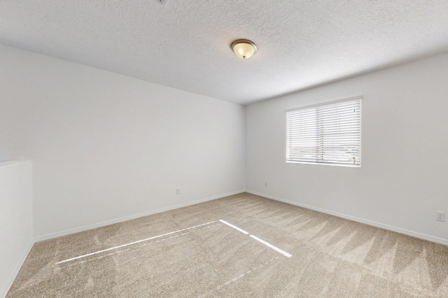 unfurnished room with baseboards, a textured ceiling, and light colored carpet