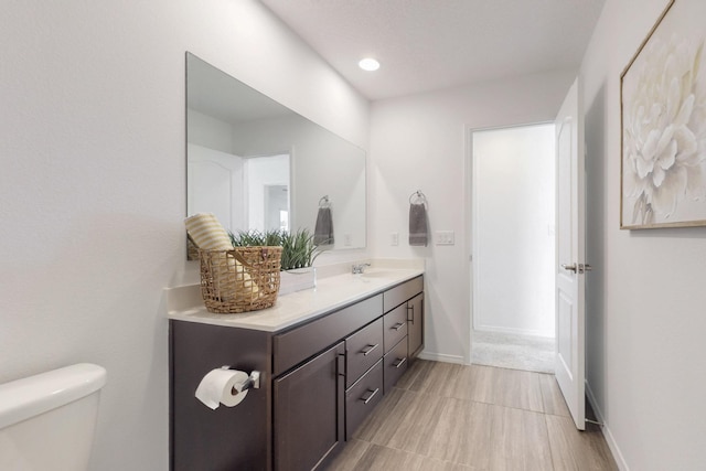 bathroom with baseboards, vanity, and toilet