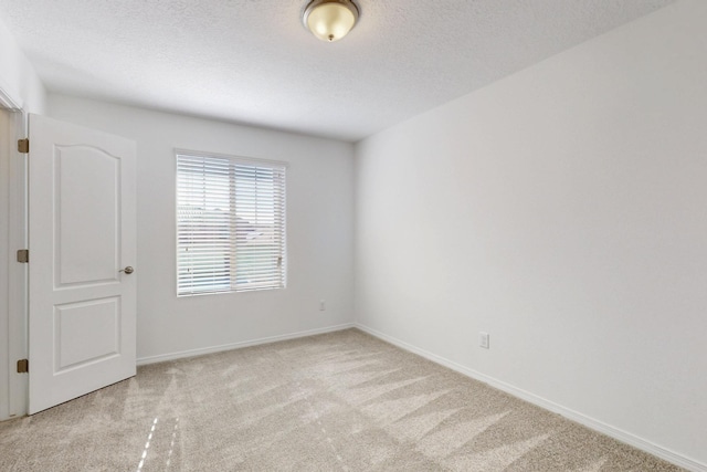 unfurnished room with light carpet, a textured ceiling, and baseboards