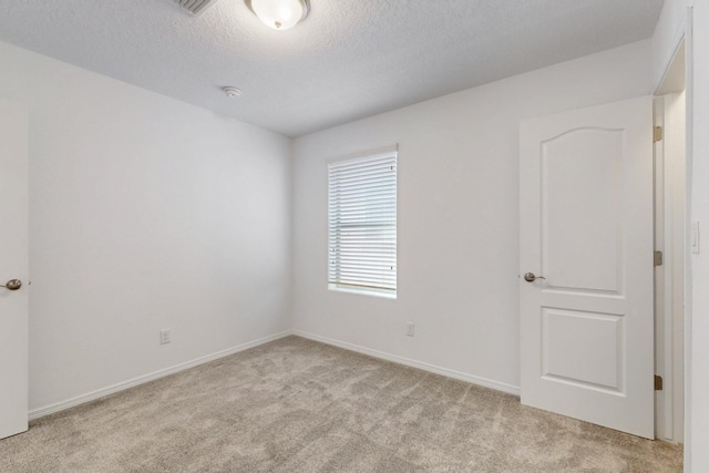 carpeted spare room with a textured ceiling and baseboards