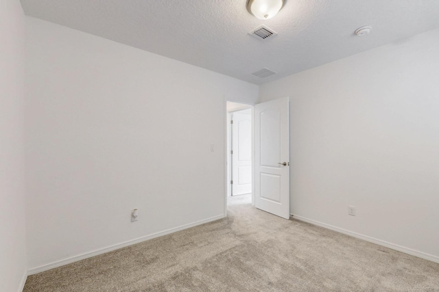 empty room featuring a textured ceiling, carpet floors, visible vents, and baseboards