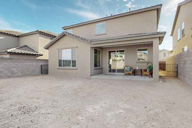 rear view of house with a patio area, fence, and stucco siding