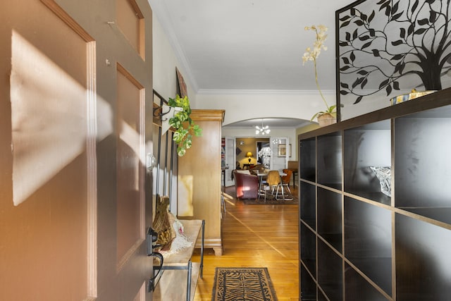 corridor featuring arched walkways, wood finished floors, and crown molding