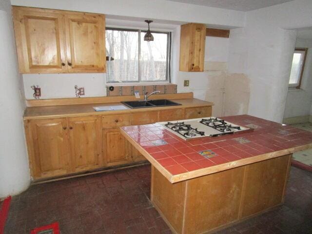 kitchen with decorative light fixtures, tile counters, white gas stovetop, a sink, and fridge