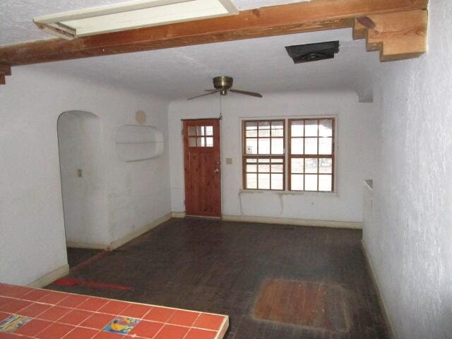 entryway featuring a healthy amount of sunlight, baseboards, arched walkways, and dark wood-style flooring