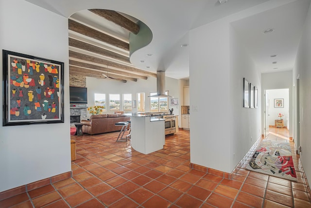 hall with beamed ceiling, dark tile patterned floors, and baseboards