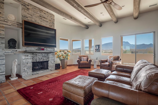 living area with a stone fireplace, a wealth of natural light, tile patterned flooring, and visible vents