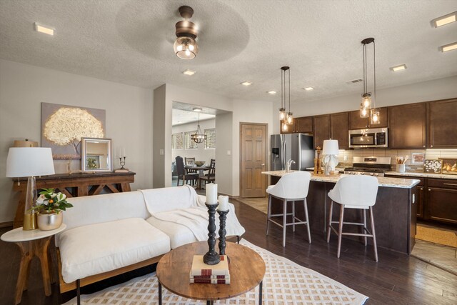 living room featuring a textured ceiling, a ceiling fan, dark wood-type flooring, and recessed lighting