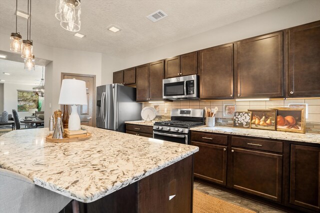 kitchen with visible vents, backsplash, appliances with stainless steel finishes, dark brown cabinetry, and light stone countertops