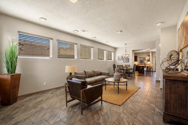 living room with visible vents, a textured ceiling, and baseboards