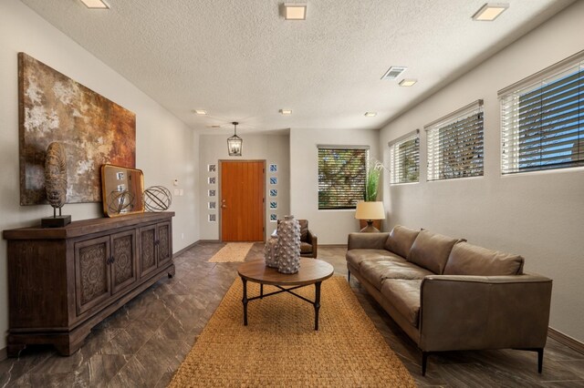 living room with visible vents, a textured ceiling, and baseboards