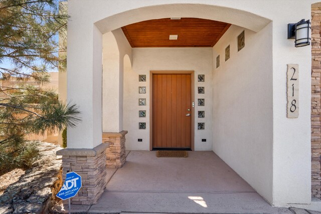 view of exterior entry featuring stone siding and stucco siding