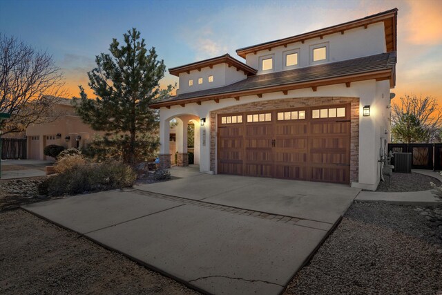 mediterranean / spanish house featuring a garage, concrete driveway, cooling unit, and stucco siding