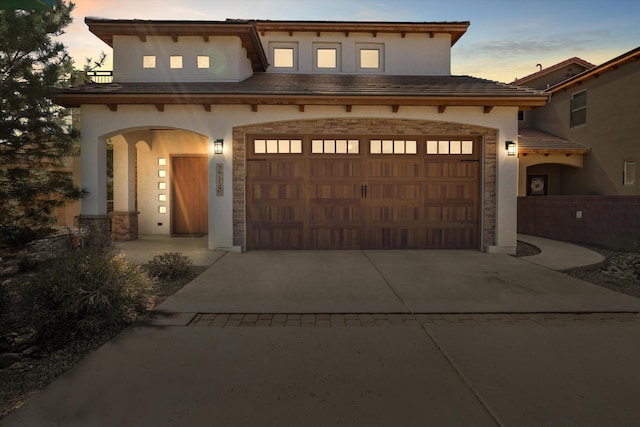 view of front of property with a garage, stone siding, and stucco siding