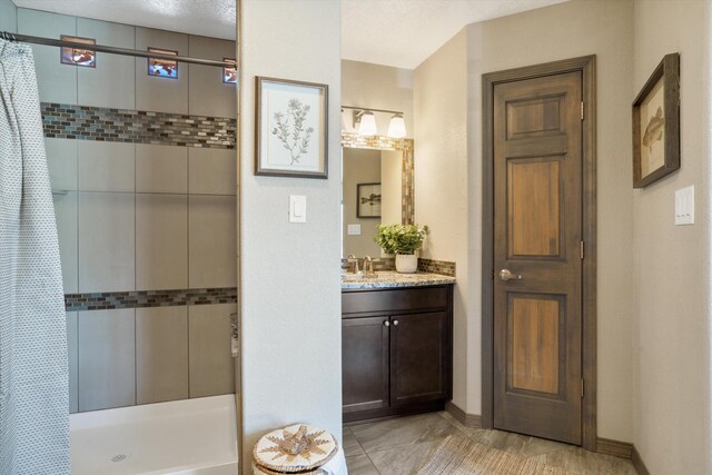 bathroom with a stall shower, vanity, and baseboards