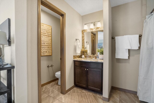 bathroom featuring tile patterned floors, vanity, toilet, and baseboards