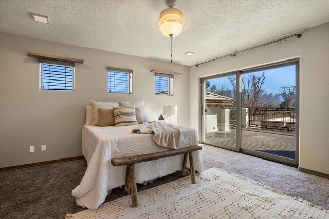 carpeted bedroom featuring access to outside, a textured ceiling, and baseboards