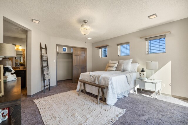 bedroom with a textured ceiling, carpet floors, a closet, and baseboards