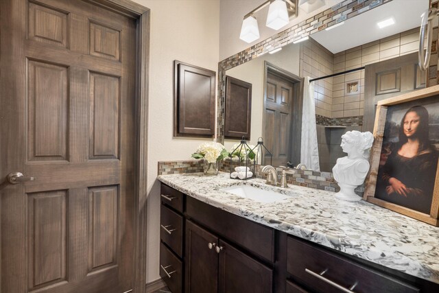 bathroom featuring tiled shower and vanity