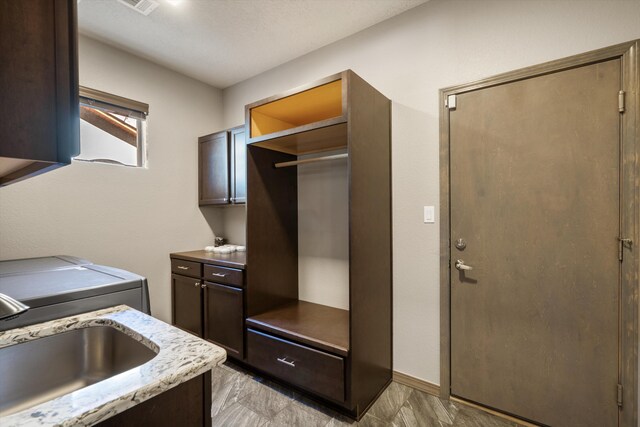 kitchen with dark brown cabinetry, washer / clothes dryer, and a sink