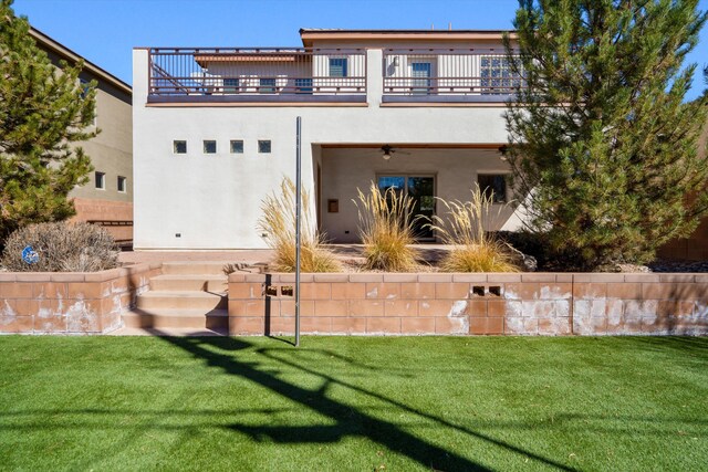 view of front facade with a balcony, a front lawn, and stucco siding