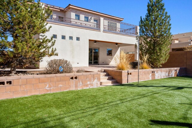 back of house featuring a yard, stucco siding, a patio area, ceiling fan, and a balcony