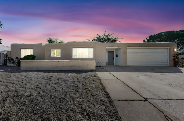 pueblo-style home featuring driveway, a garage, and stucco siding