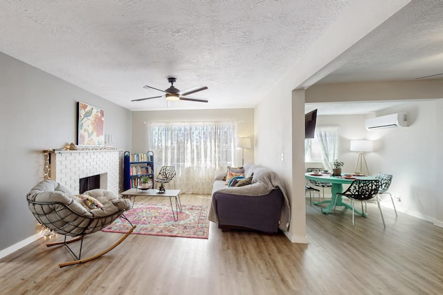 living area with a fireplace, a wall mounted air conditioner, wood finished floors, and a healthy amount of sunlight