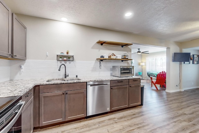 kitchen with a toaster, light wood-style flooring, light stone countertops, stainless steel appliances, and a sink