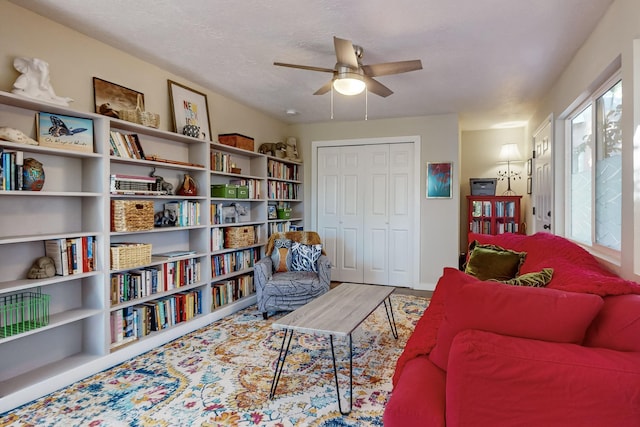 living area featuring a healthy amount of sunlight, a textured ceiling, a ceiling fan, and wood finished floors