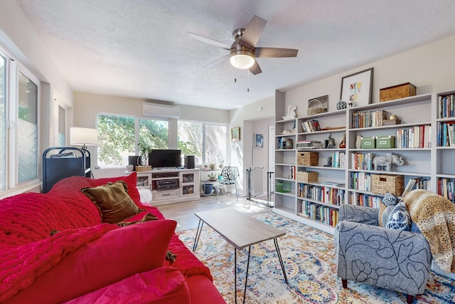 living room with a ceiling fan, wood finished floors, a textured ceiling, and a wall mounted AC