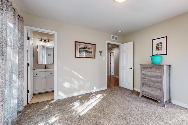 unfurnished bedroom featuring ensuite bath, baseboards, visible vents, and light colored carpet