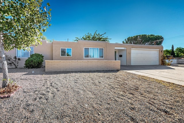 pueblo-style house with concrete driveway, an attached garage, and stucco siding