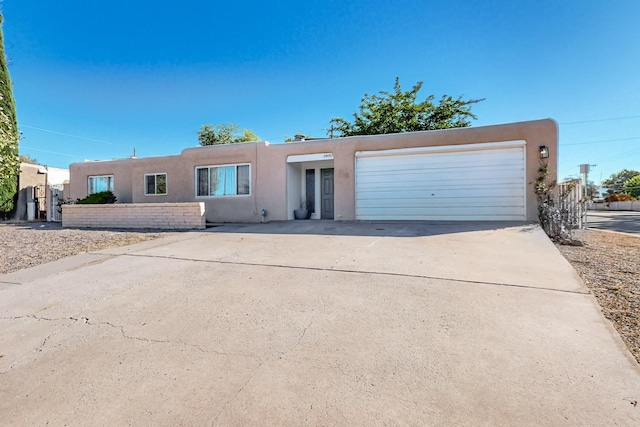 adobe home featuring concrete driveway, an attached garage, and stucco siding